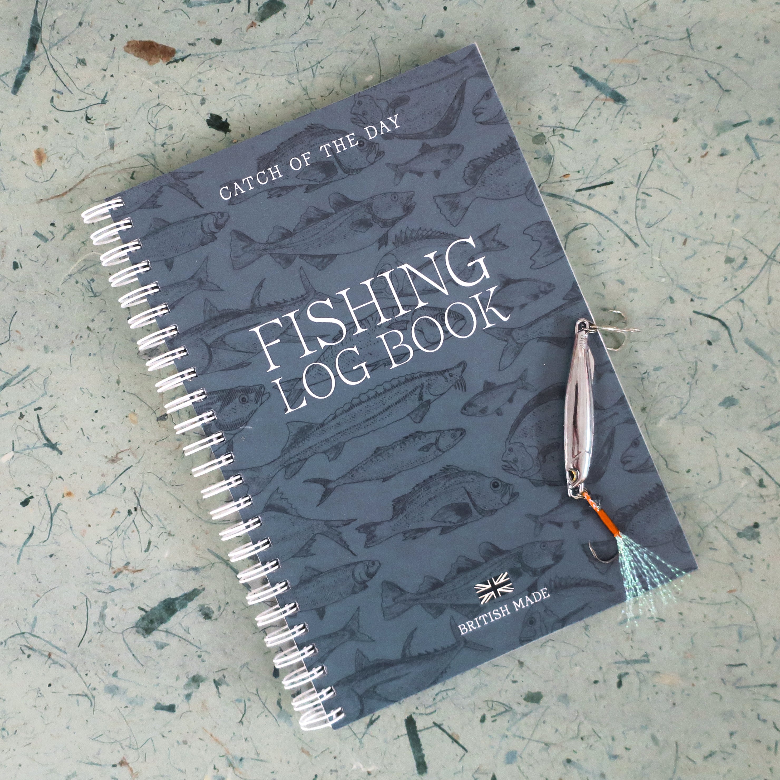 Fishing log book with fishing lure on a textured surface