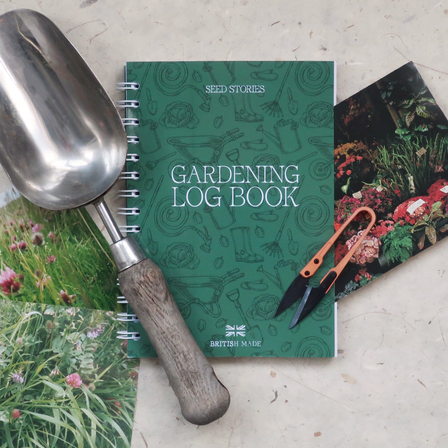 Gardening log book with gardening tools, with vintage garden plants photographs on a textured surface