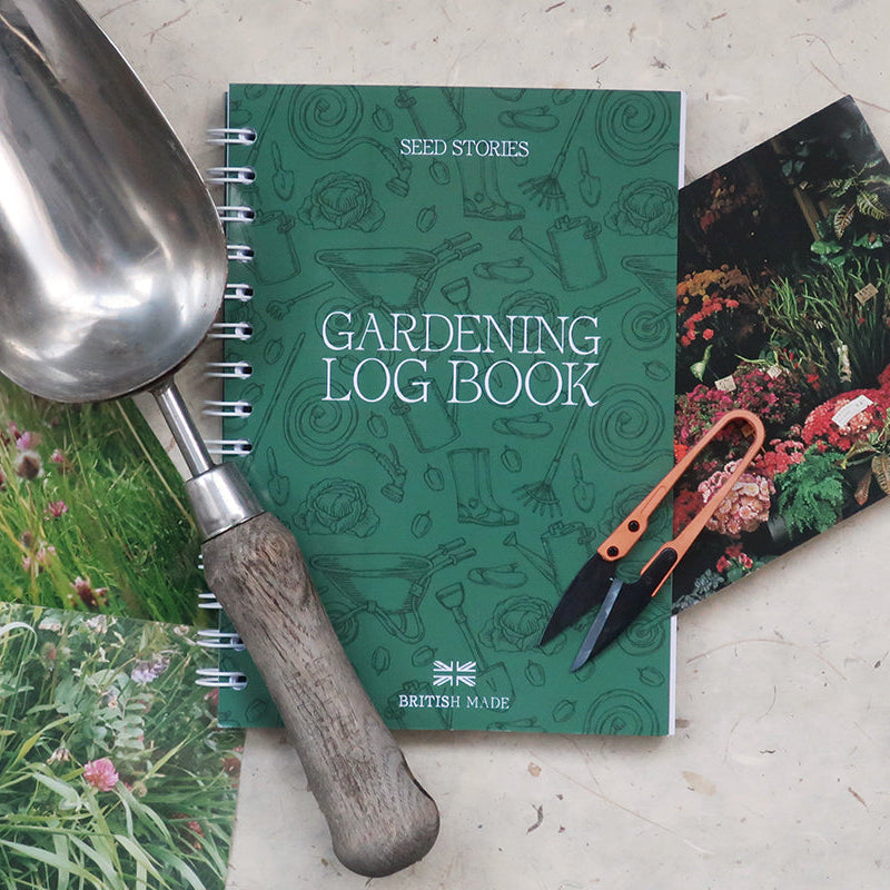Gardening log book with trowel and scissors on a light background