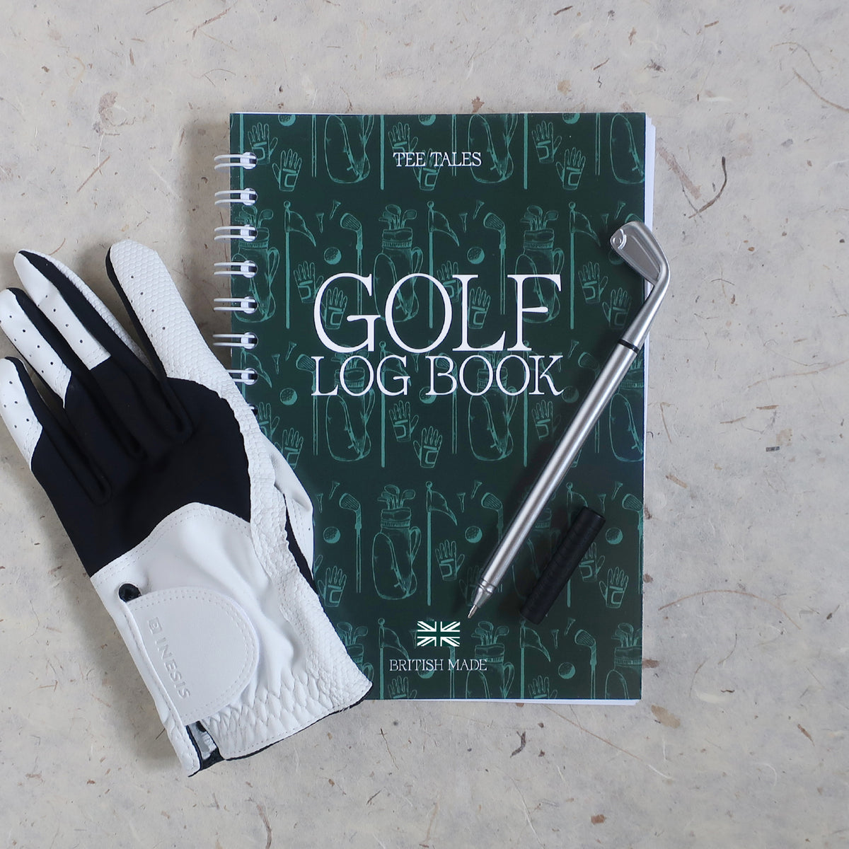 wayzgoose Golf Log Book On A Cream Textured Background With A Golf Club Pen & White Golf Club Laid On Top