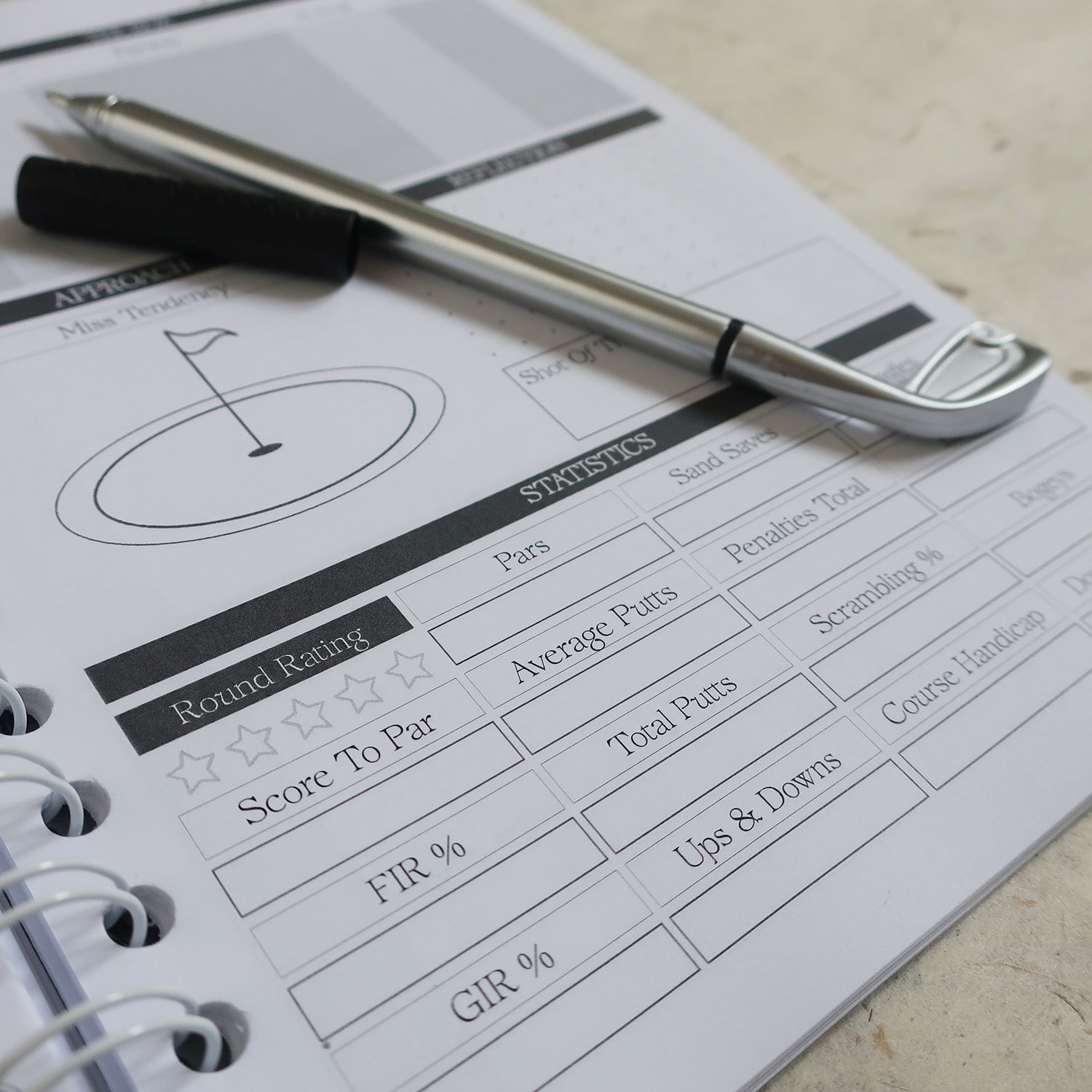 Golf Log Book Open On Round Statistics Page With A Golf Club Pen Laid On Top