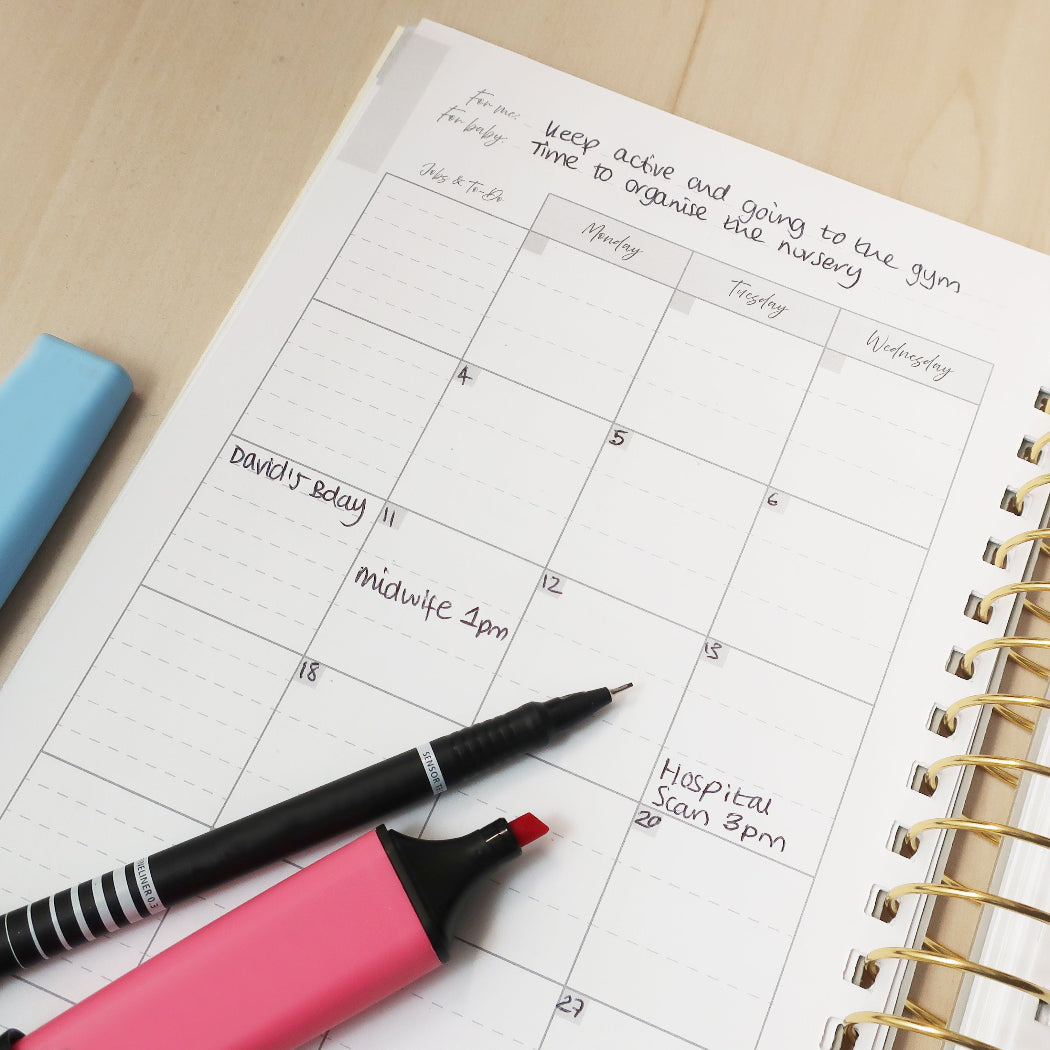 Calendar page with handwritten notes and appointments and a pen and highlighter on a wooden desk