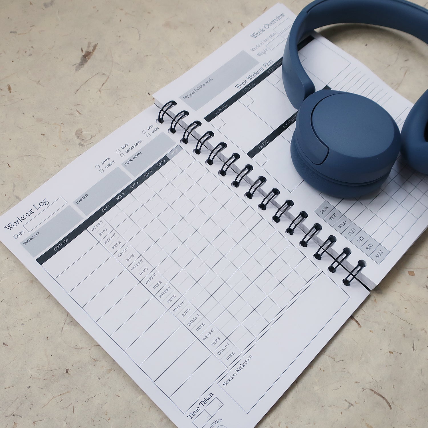 Spiral bound workout log book, with a grid page to log the exercise, the sets, weights and reps.