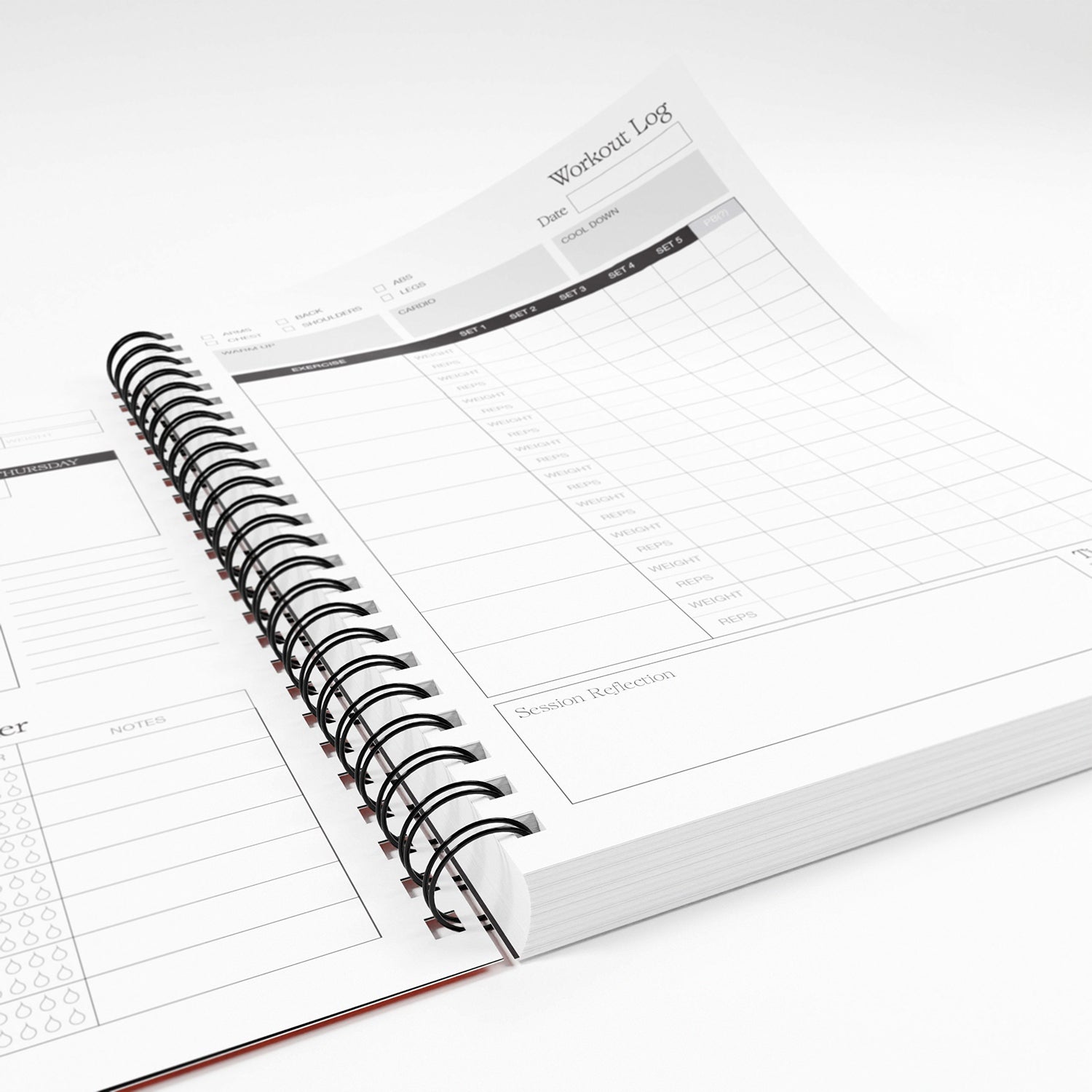 Spiral-bound workout planner with workout log pages on a white background