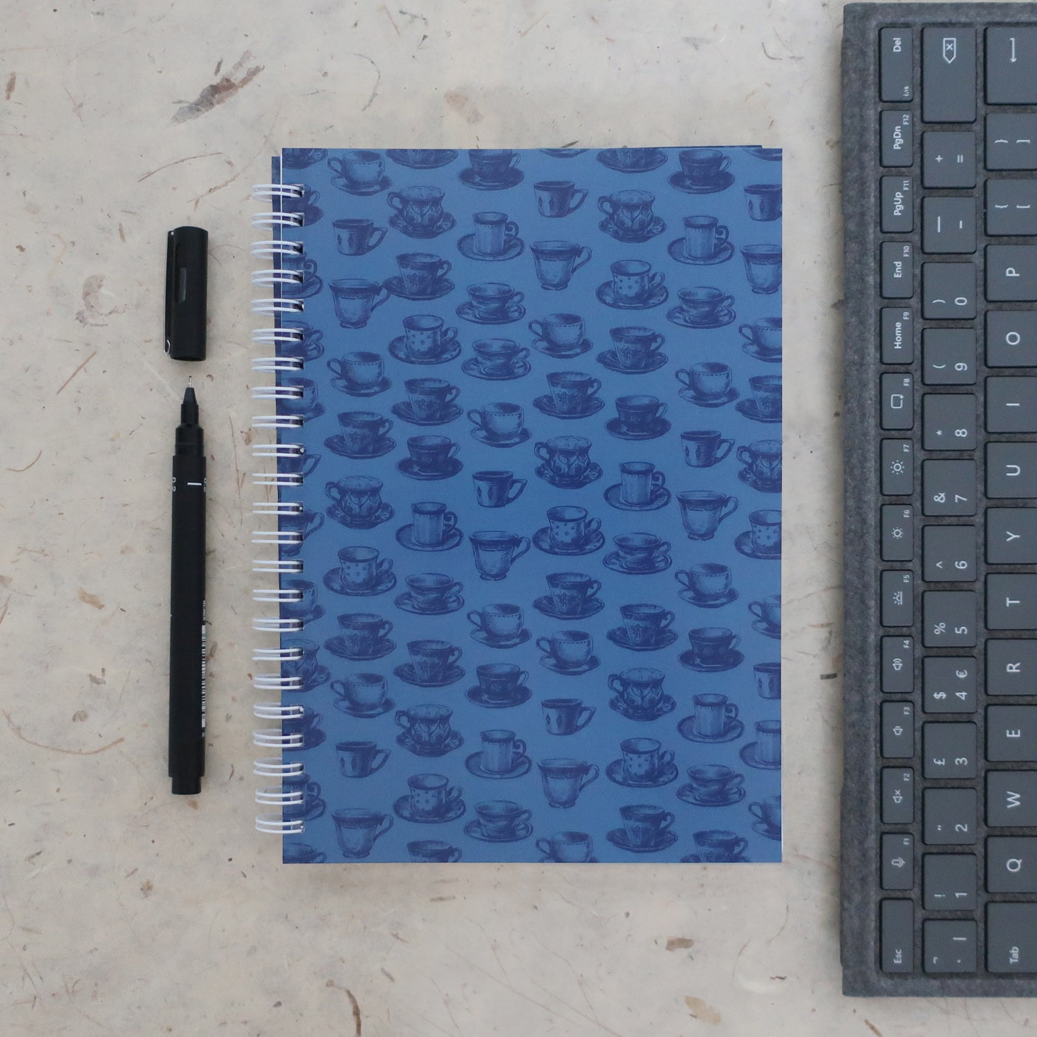 Address & password log book in a tea cup print with a pen and keyboard on a textured surface