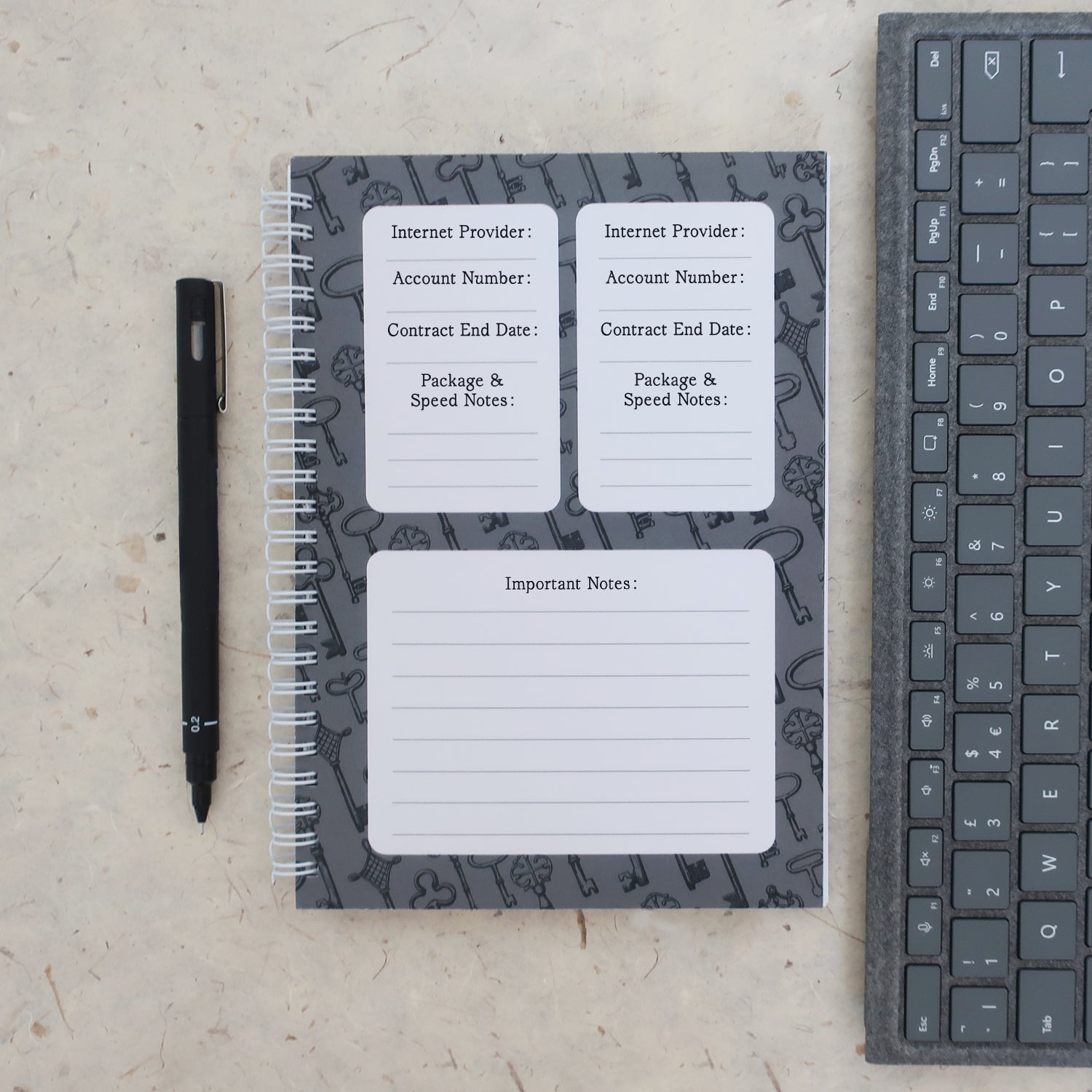 Address & password log book open on internet provider information page with a pen and keyboard on a textured surface